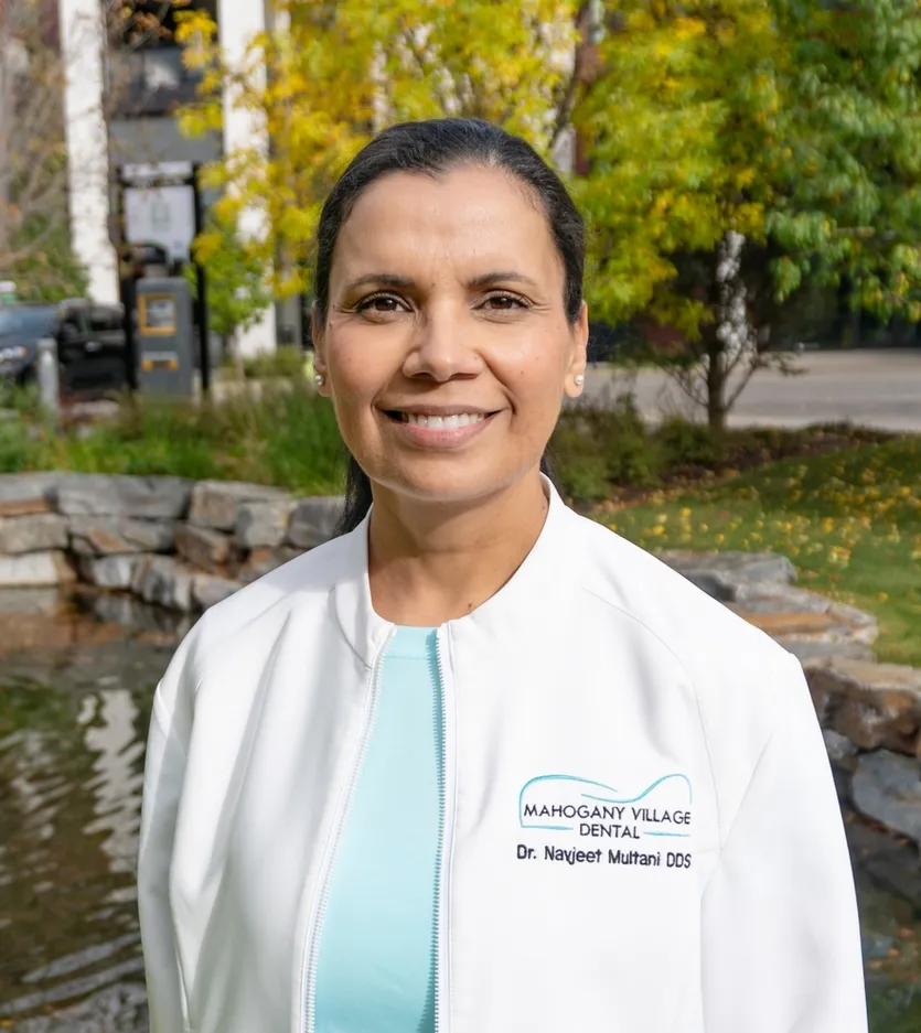 Dr. Navjeet Multani, dentist at Mahogany Village Dental, smiling beside the pond near the clinic